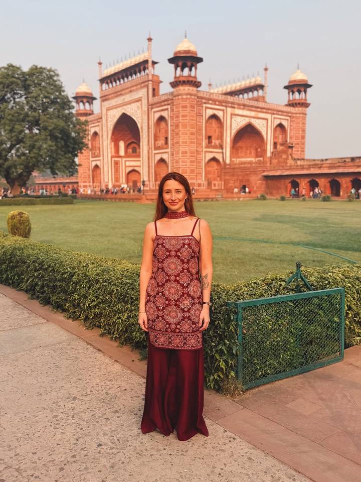 Vrouw die voor een historisch rood zandstenen gebouw staat.