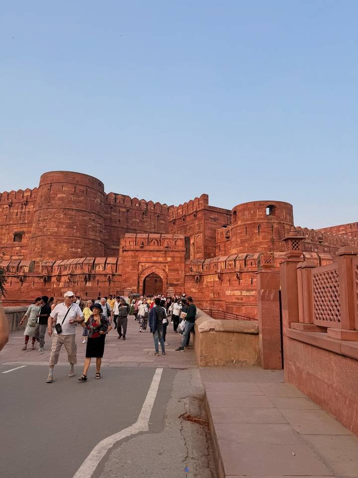 Toeristen gevulde ingang naar een rood zandstenen fort met kantelen.