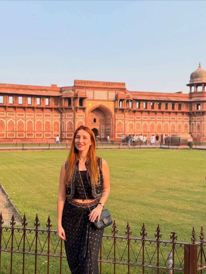 Vrouw poseert bij een groot rood historisch gebouw.