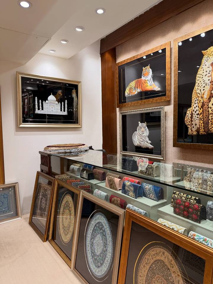 Interieur van een winkel met geborduurd textiel en ingelijste kunst.