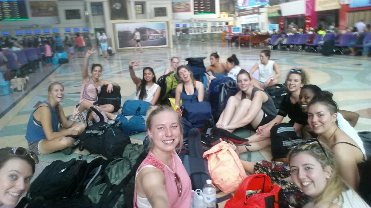 Large group sitting on the floor in a train station.