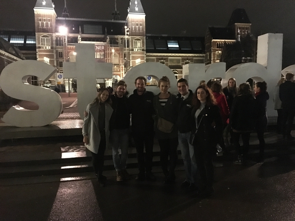 Group photo in front of an iconic sign at night.