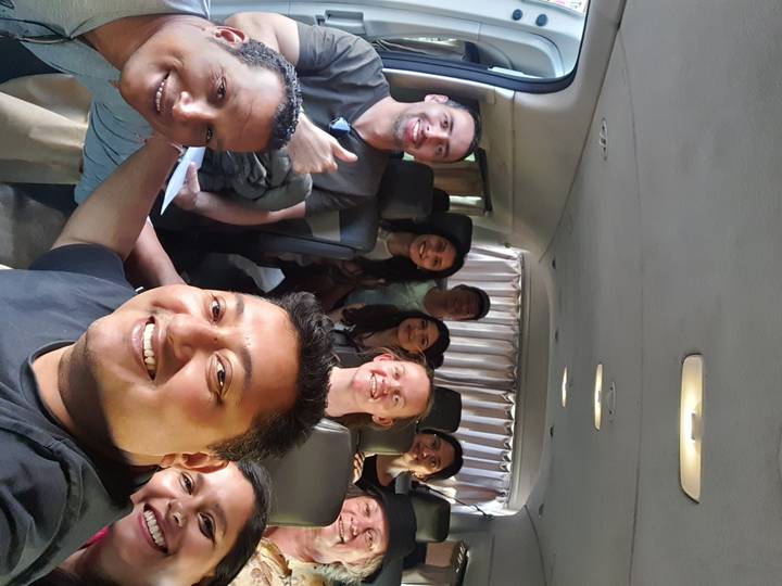 Group of people sitting inside a vehicle posing for a selfie.