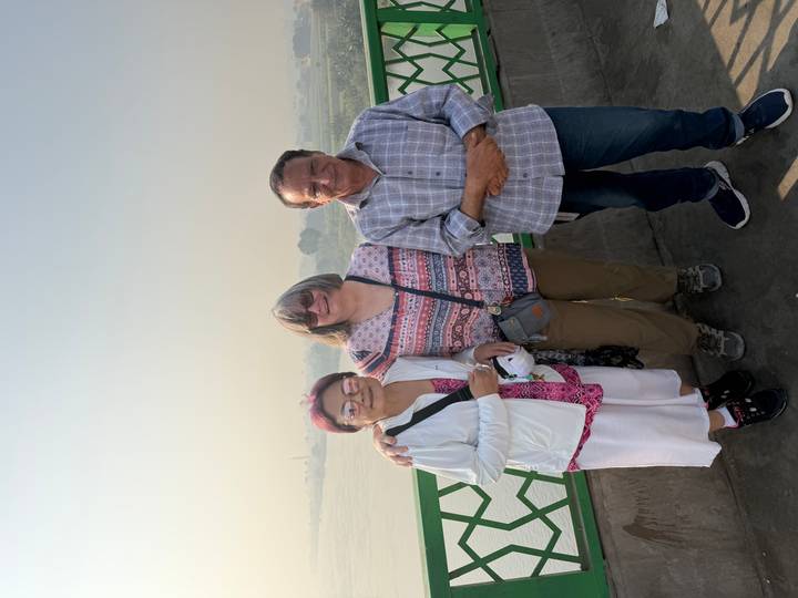 Zwei Frauen posieren mit einem Mann neben einem Flussblick.