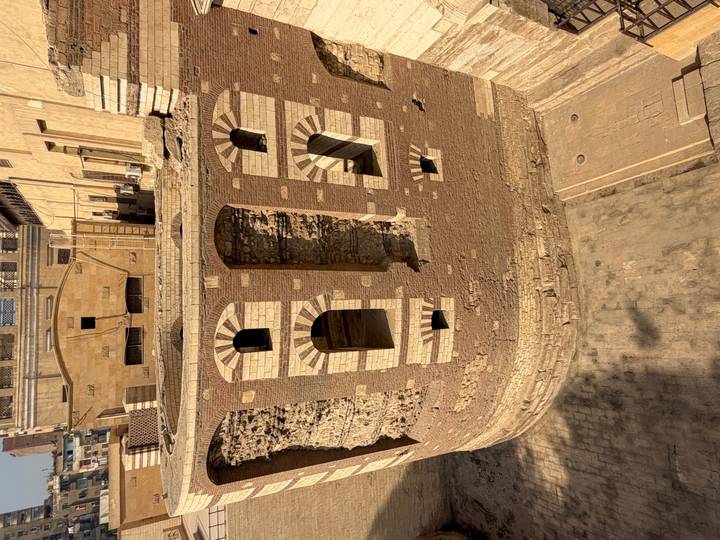 Antike römische Ruine mit gewölbten Fenstern und einem zylindrischen Bauwerk.