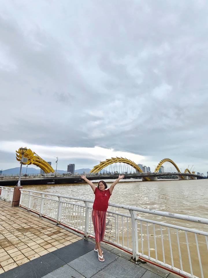 Personne posant les bras levés devant un pont en forme de dragon.
