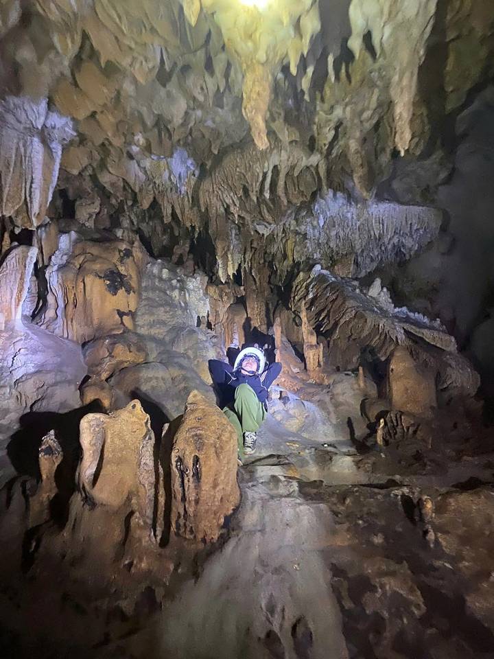 Personne explorant une grotte avec des stalactites et des stalagmites.