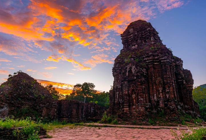 Ruines d'un temple antique avec des couleurs vives de coucher de soleil dans le ciel.