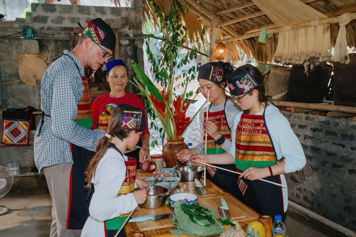 Groupe de personnes préparant de la nourriture dans un cadre traditionnel.