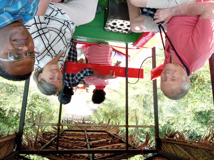 Groep mensen die rijden op een rood en groen voertuig in een bosgebied.