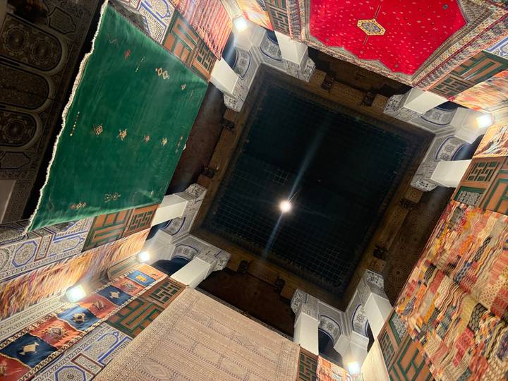 Interior of a building with colorful carpets hanging from the ceiling.