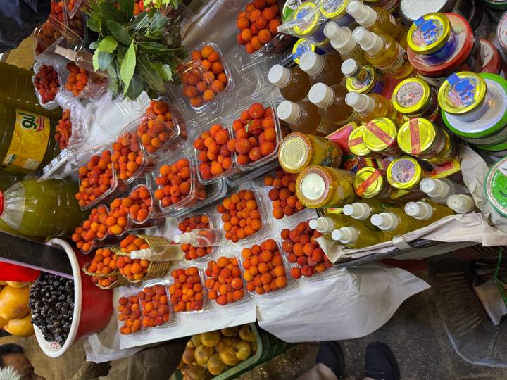 Puesto de mercado con frutas rojas y condimentos.
