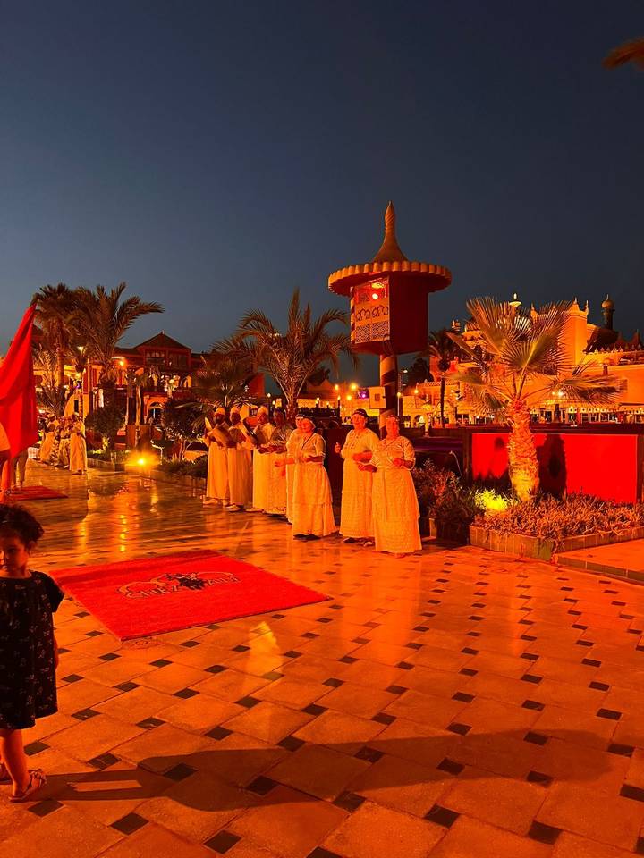 Scène de nuit avec des artistes en tenue traditionnelle en plein air.