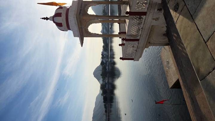 Pavillon au bord du lac avec des collines en arrière-plan.