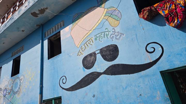 Mur bleu avec une moustache peinte et des lunettes de soleil.