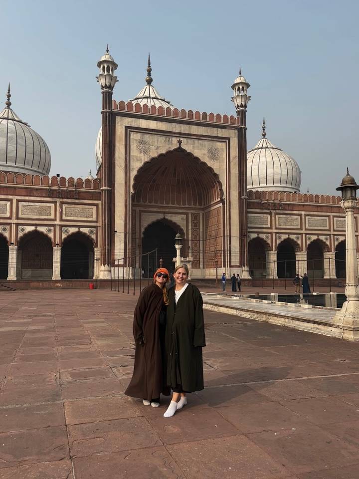 Deux personnes debout devant une mosquée ornée.