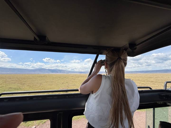 Person, die von einem Safari-Fahrzeug aus durch ein Fernglas schaut.