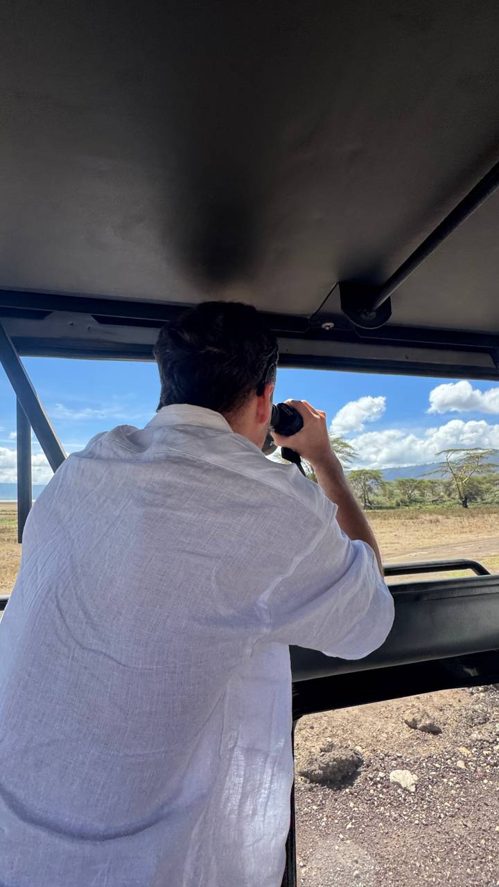 Person mit Fernglas, mit Safari-Landschaft draußen.