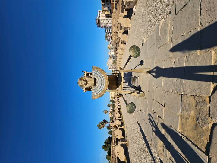 Antikes Denkmal mit einer Skulptur unter klarem Himmel.