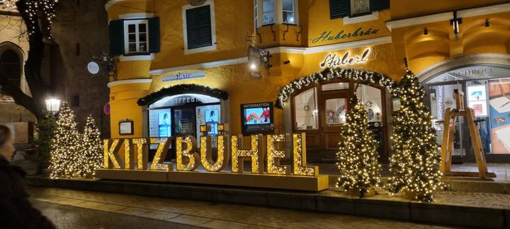 Kitzbühel bord met decoratieve verlichting op een gebouwgevel.