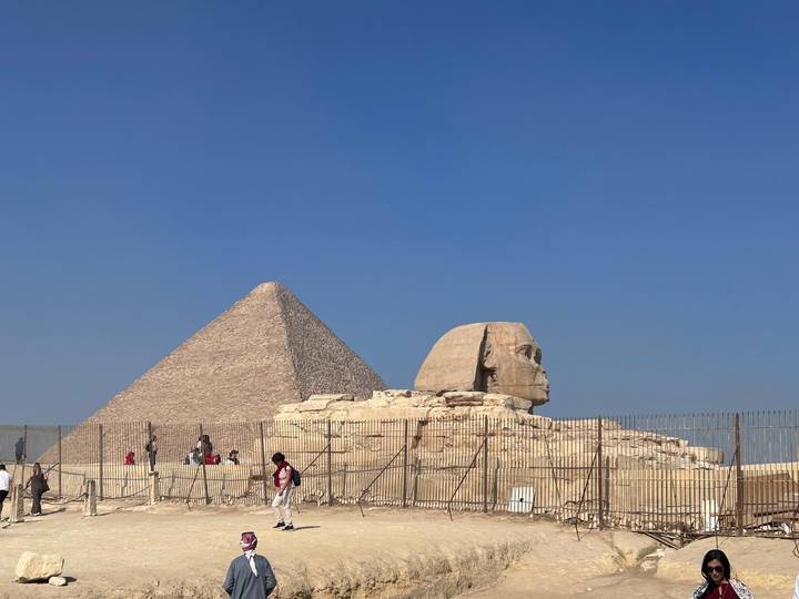 Le Sphinx et la Pyramide de Gizeh avec des visiteurs qui se promènent autour.