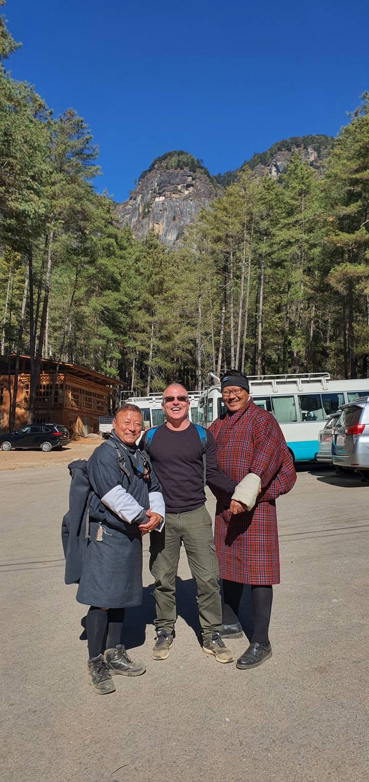 Grupo de personas de pie y sonriendo en un entorno al aire libre con árboles.
