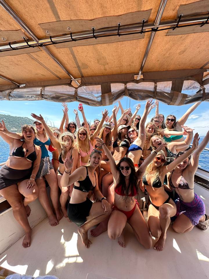 Group of people in swimwear lounging under a canvas cover.