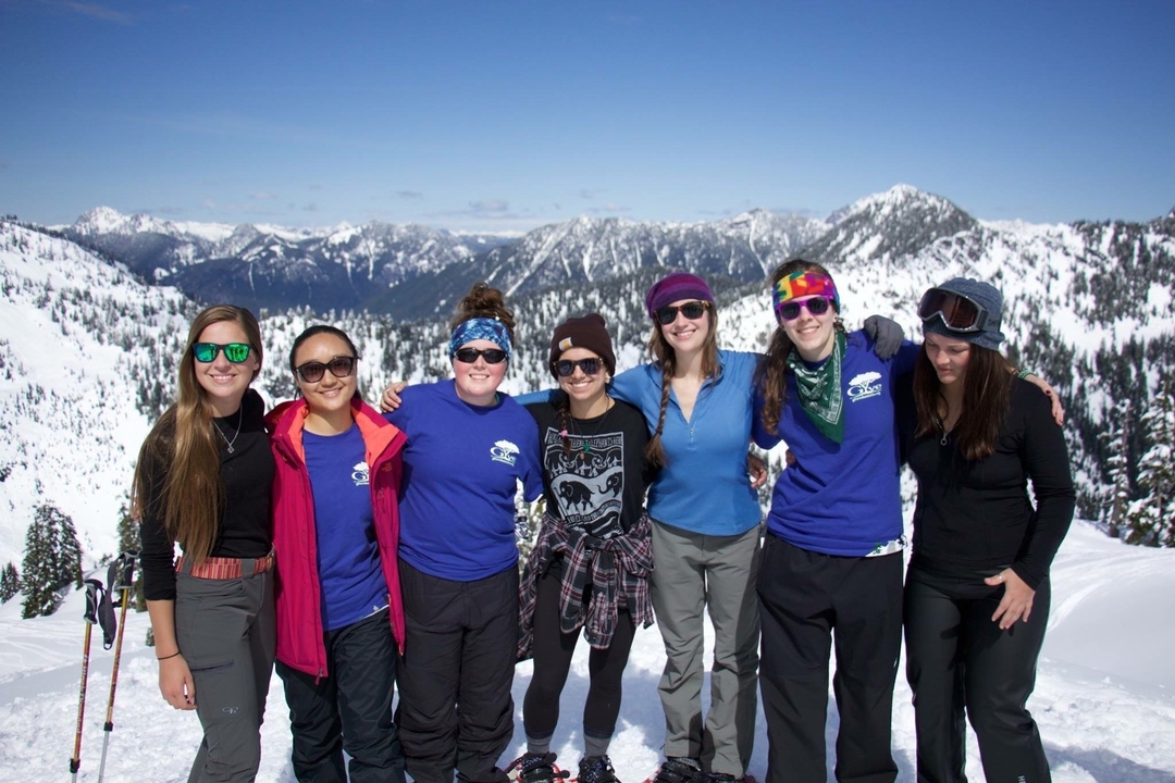 A group of friends posing in front of a snowy mountain landscape.