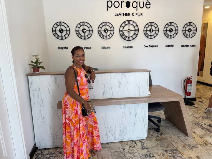 Frau steht vor einem Empfangstresen mit Stadtuhren an der Wand.