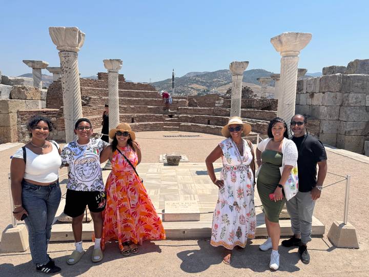 Gruppe von Menschen, die an einer antiken Stätte mit Säulen und Ruinen posiert.