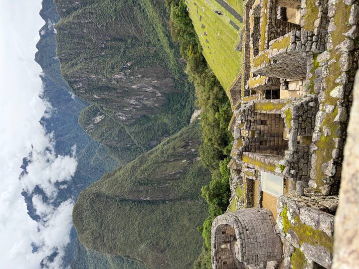 Machu Picchu ruïnes met omliggende bergen onder een bewolkte hemel.