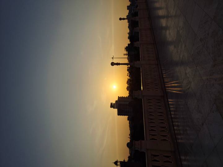 Puesta de sol sobre un paisaje urbano con una barandilla en primer plano.