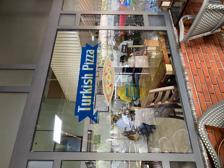 Enseigne indiquant 'Pizza Turque' sur la vitrine d'un restaurant.
