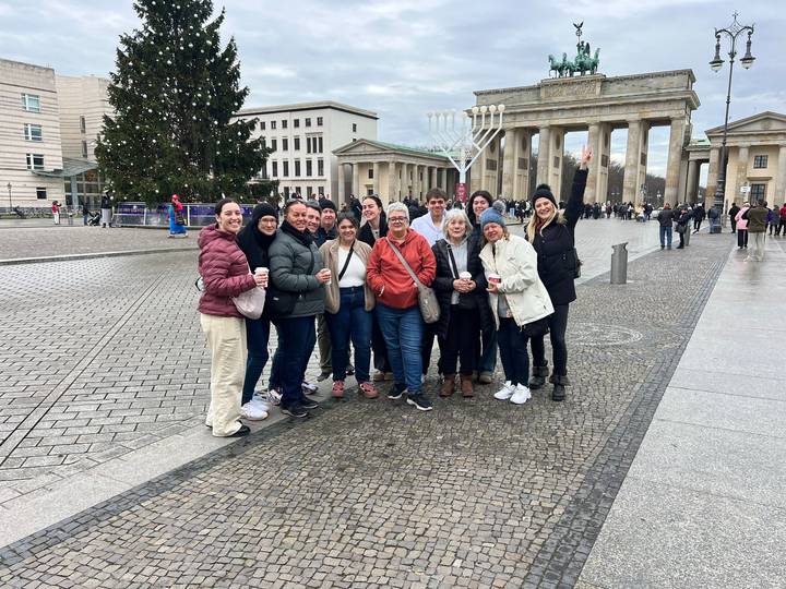 Photo de groupe devant la porte de Brandebourg avec un sapin de Noël à proximité.