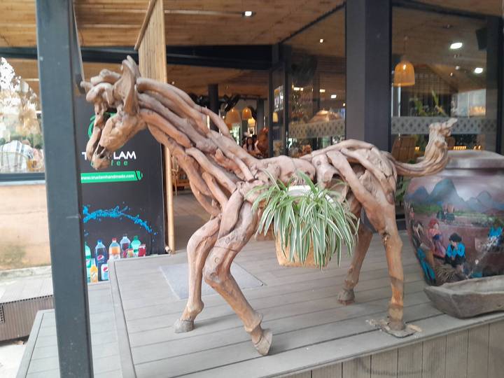 Sculpture en bois ressemblant à un animal devant un café.