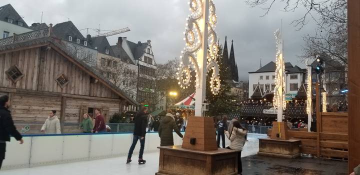 Mensen die schaatsen in een feestelijke omgeving, kathedraal op de achtergrond.