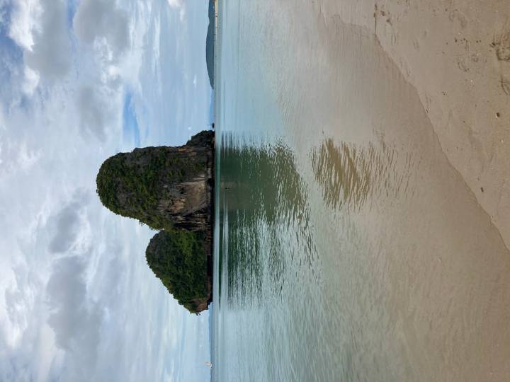 Rock formations in the sea viewed from a sandy beach.