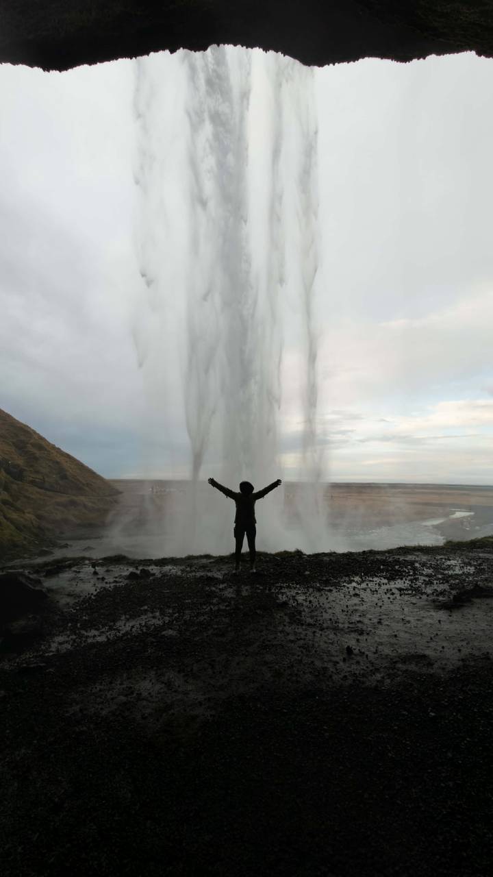 Persona de pie con los brazos abiertos de par en par frente a una gran cascada.