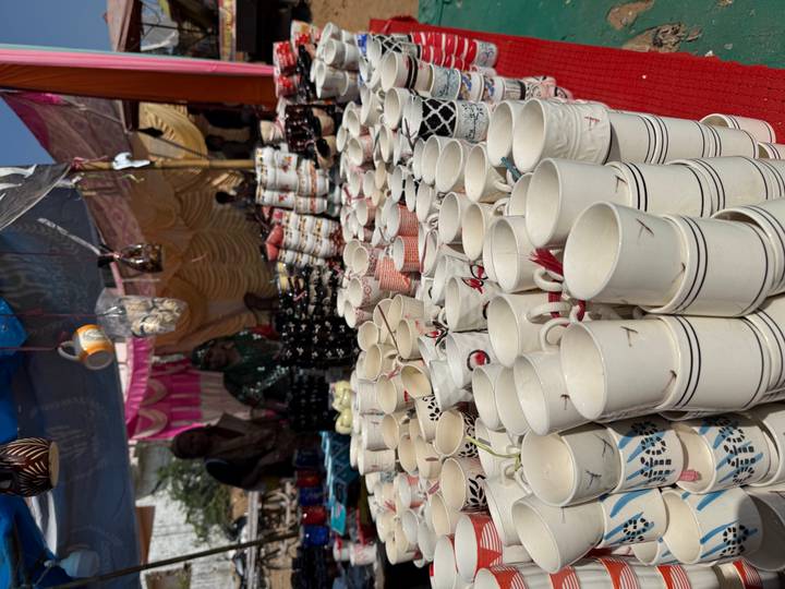 Puesto de mercado con pilas de tazas y cerámicas.