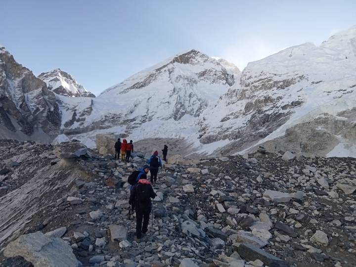 Excursionistas en terreno rocoso con un telón de fondo de montañas nevadas.