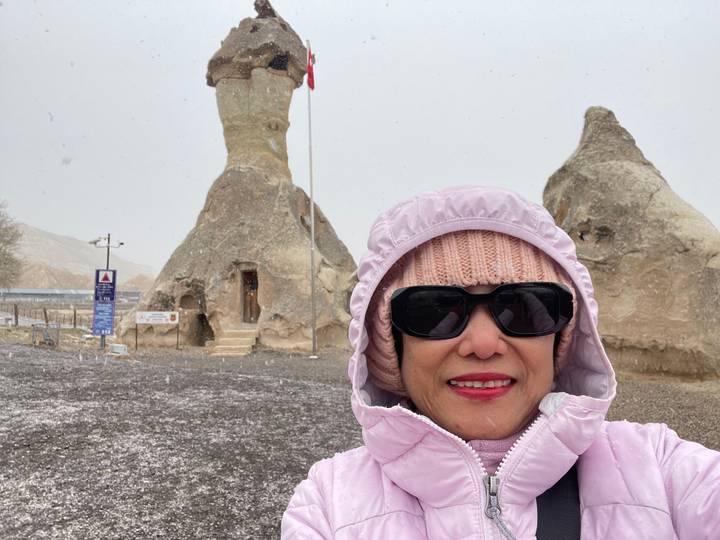 Woman sitting on a decorative bench with hills in the background.