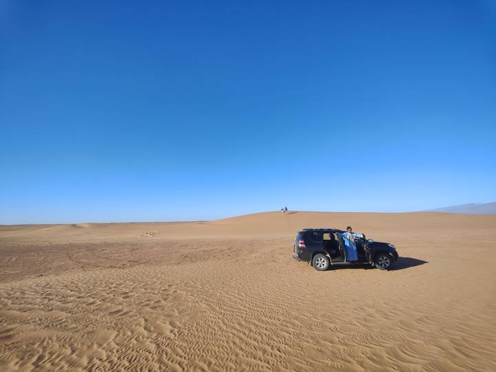 Une voiture dans un vaste paysage désertique.