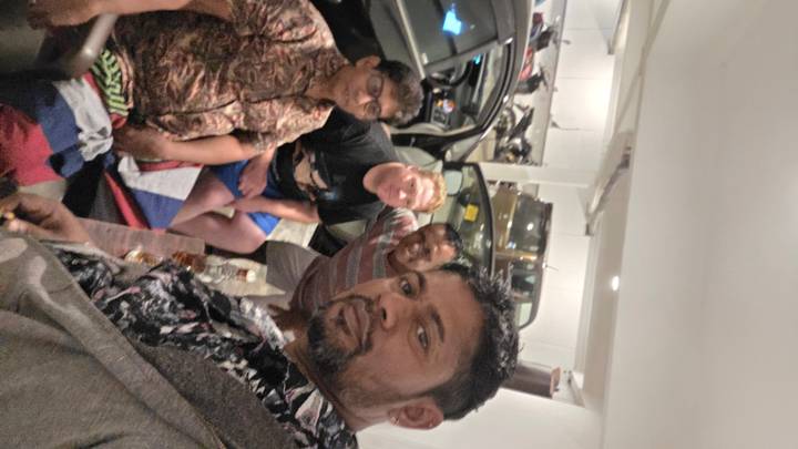 Grupo de cuatro personas en un área de estacionamiento, toma borrosa.