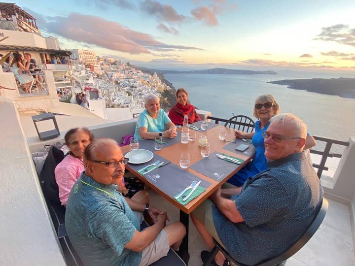 Repas de groupe en plein air avec vue sur mer, bâtiments blancs sur les falaises.