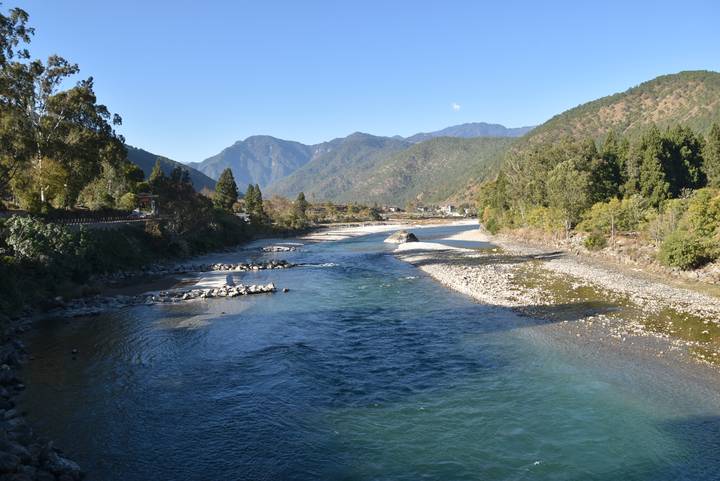 Fluss, der in einem von Bäumen umgebenen Tal fließt.