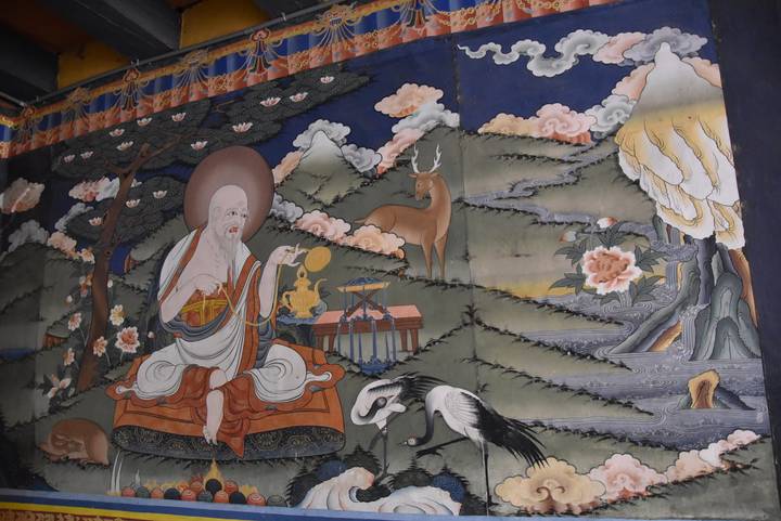 Großes Wandgemälde, das eine religiöse Figur mit einer ruhigen Naturszene darstellt.