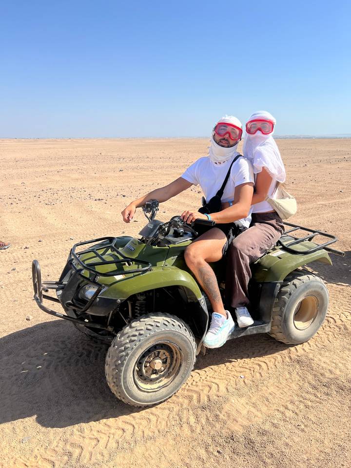 Two people on an ATV in a desert area.