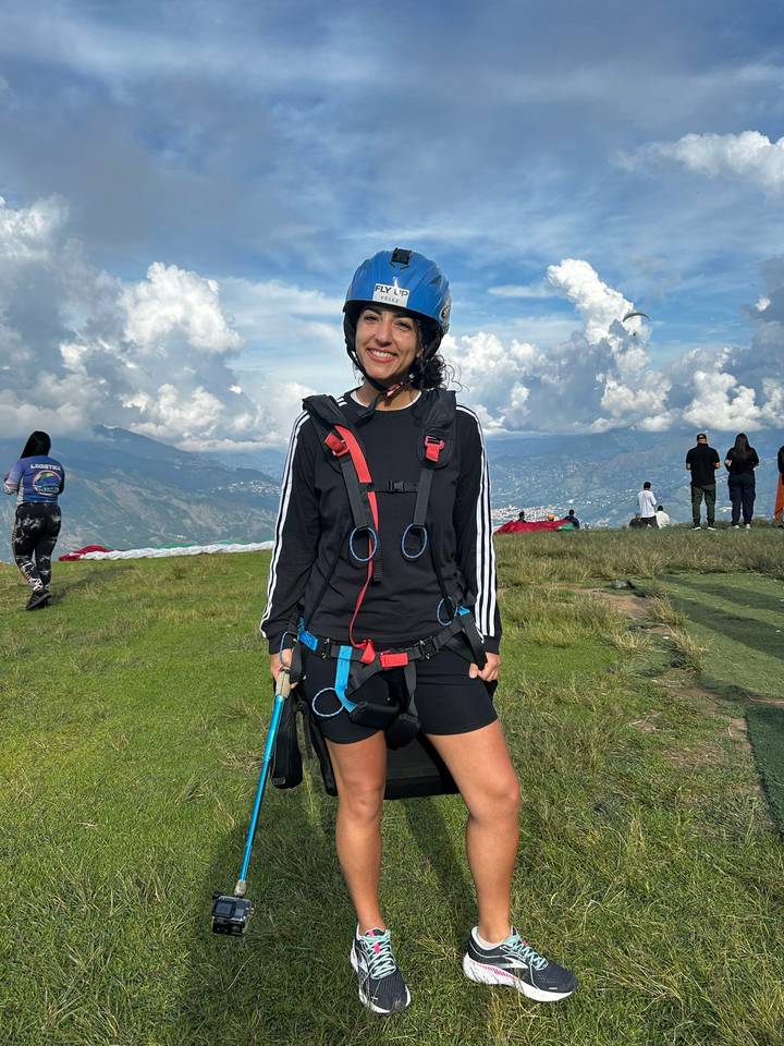 Persona preparada para parapente con colinas y nubes al fondo.