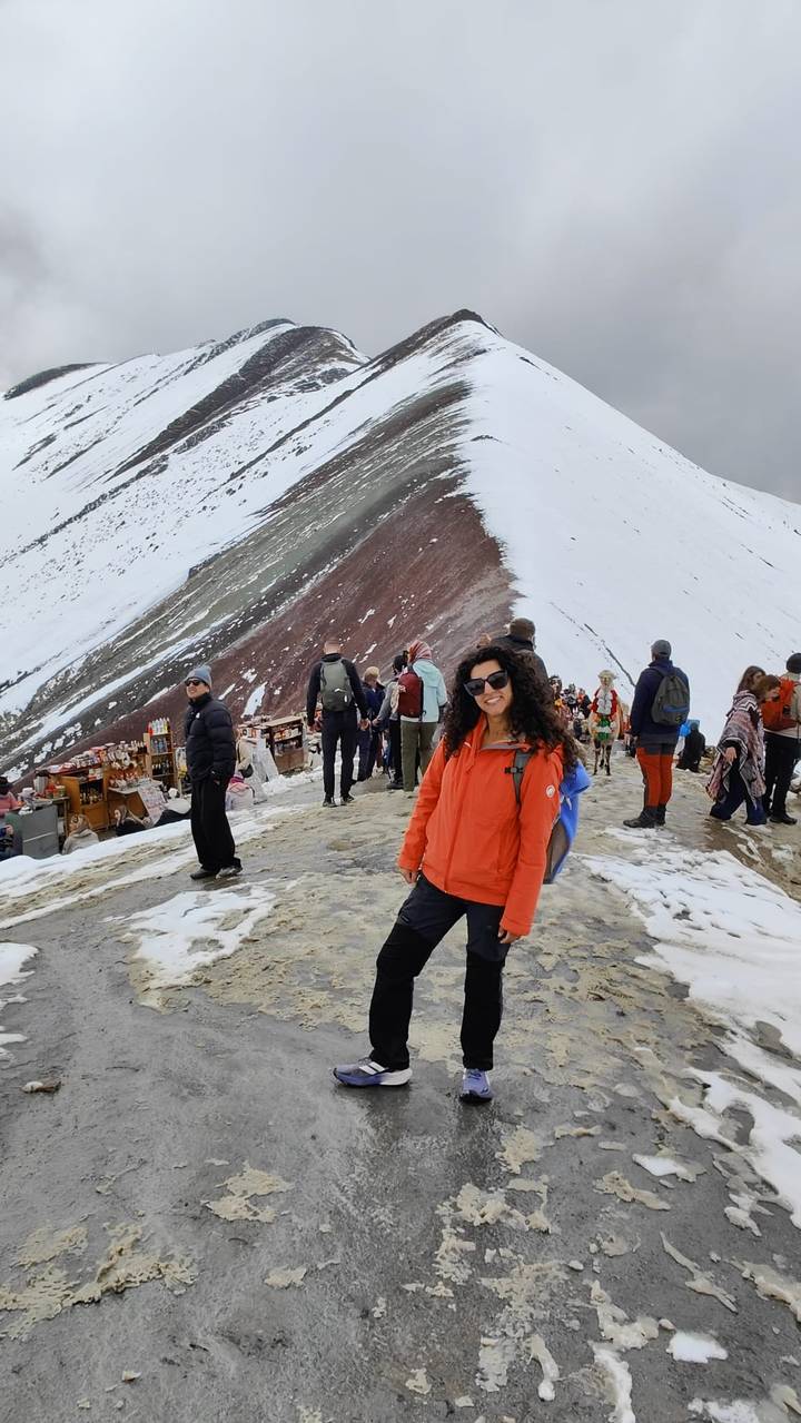 Turista posando en un sendero montañoso nevado en medio de un grupo de excursionistas.
