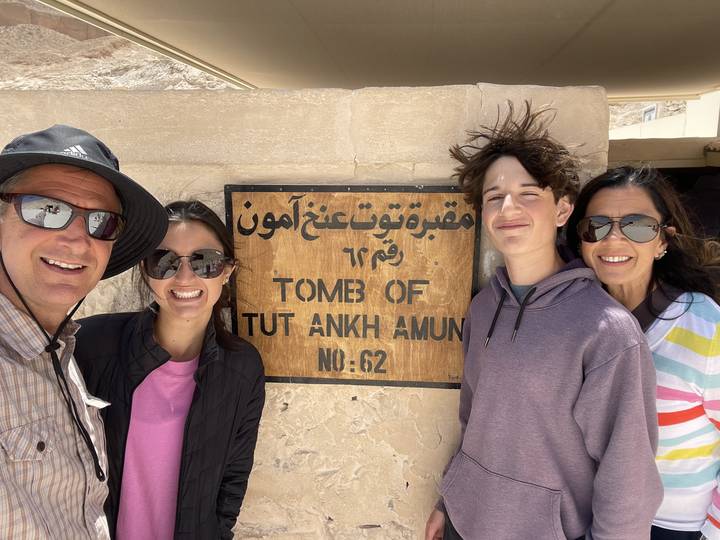 Four people in front of a sign at an archaeological site.